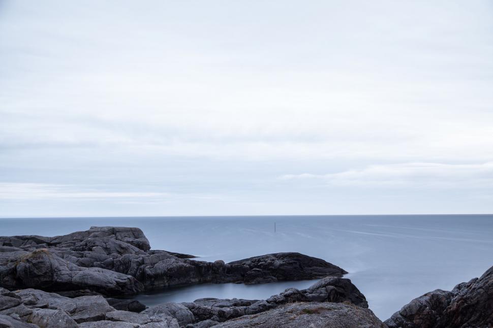 Free Image of Man Standing on Rocky Beach Near Ocean 