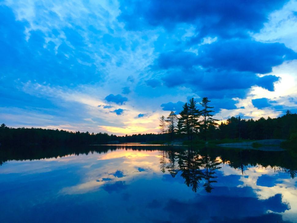 Free Image of Lake Surrounded by Trees Under Cloudy Sky 
