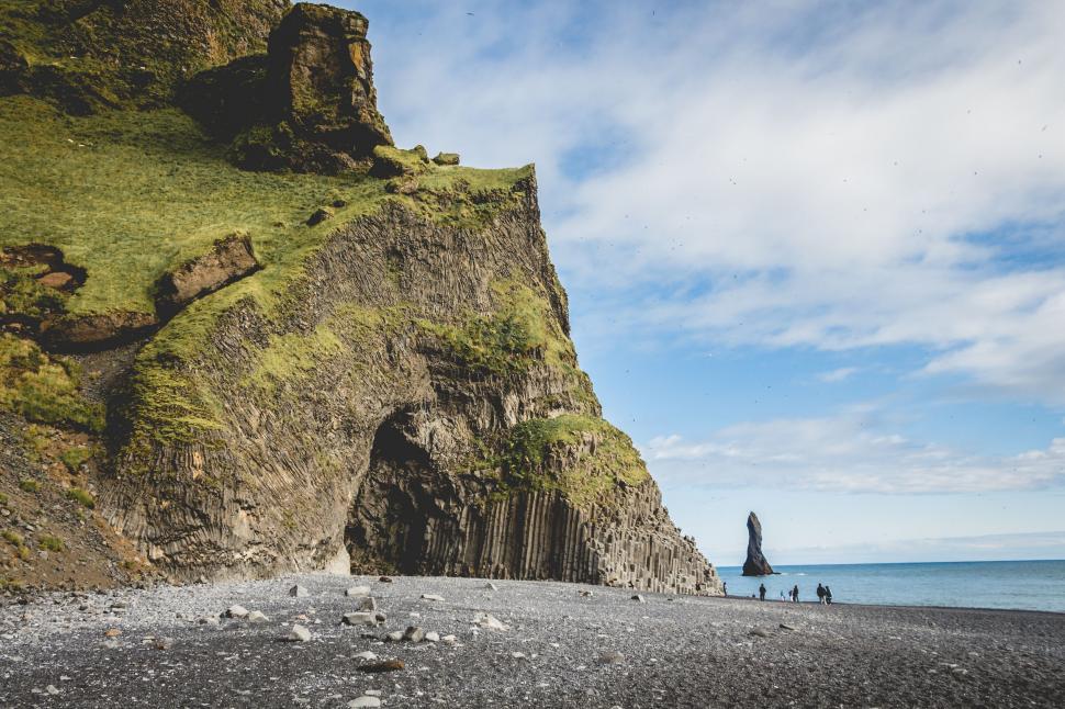 Free Image of Two People Walking on a Rocky Beach Near the Ocean 