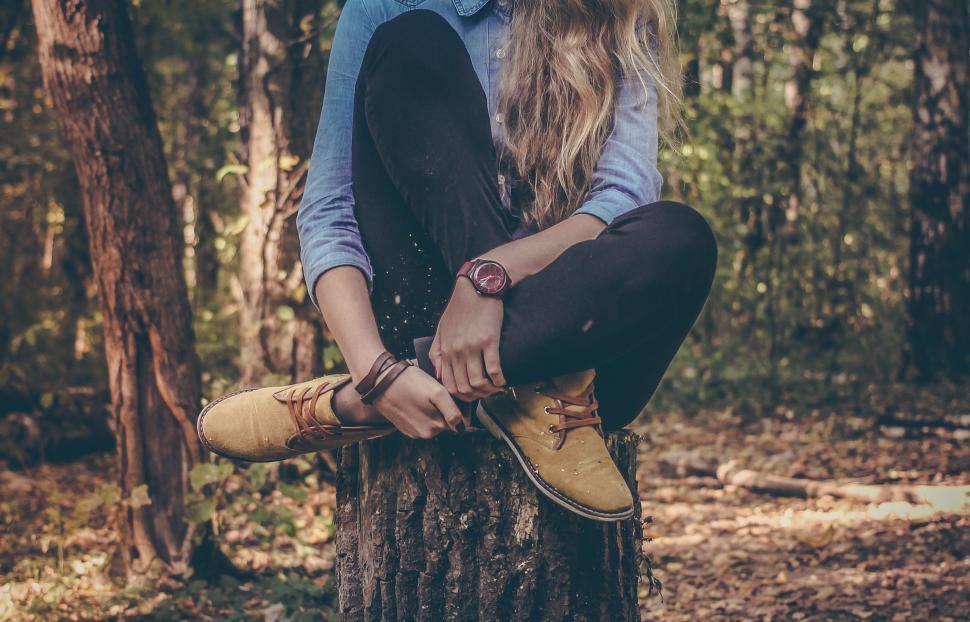 Free Image of Woman Sitting on Top of Tree Stump 