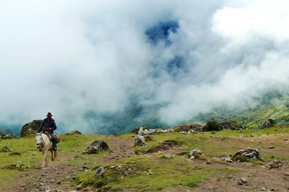 Free Image of Man Riding Horse on Lush Green Hillside 
