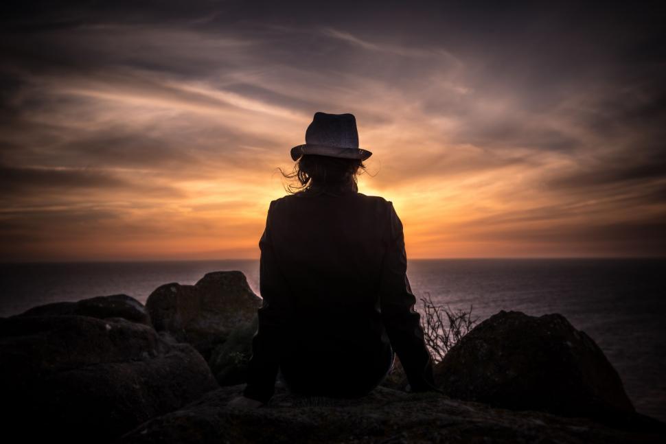 Free Image of Person Sitting on Top of Rock Near Ocean 
