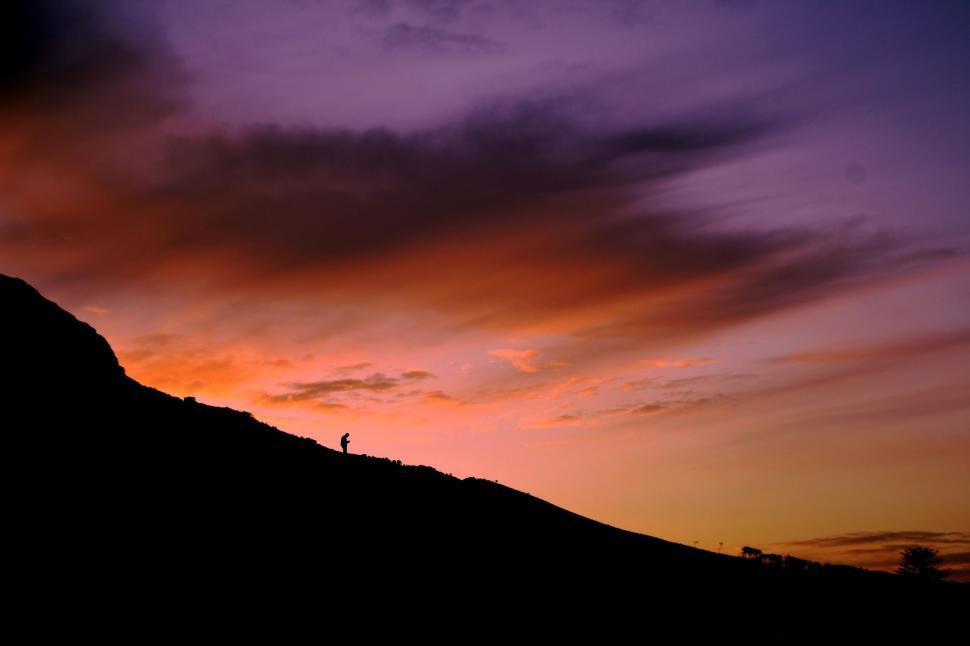 Free Image of Person Standing on Top of Hill at Sunset 