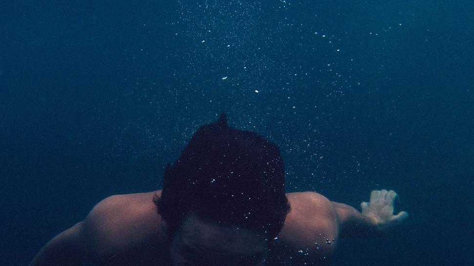 Free Image of Man Swimming With White Frisbee 