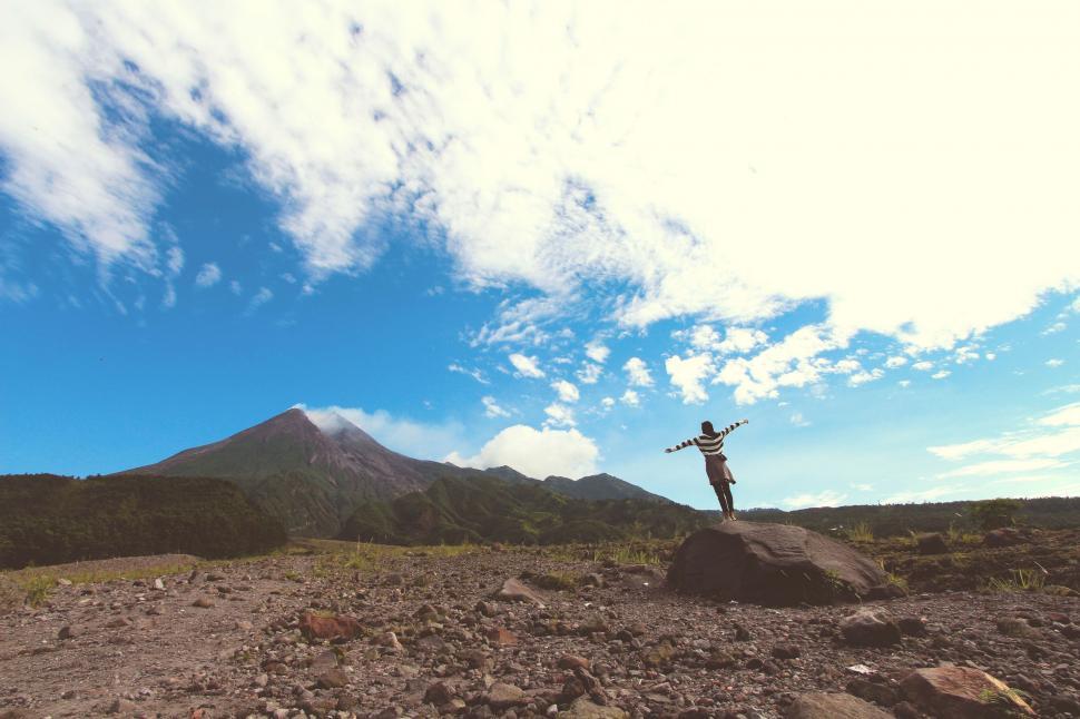 Free Image of Man Standing on Top of Large Rock 