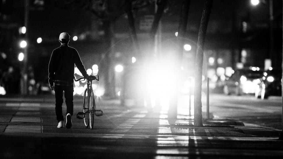 Free Image of Man Walking Bike Down Street at Night 
