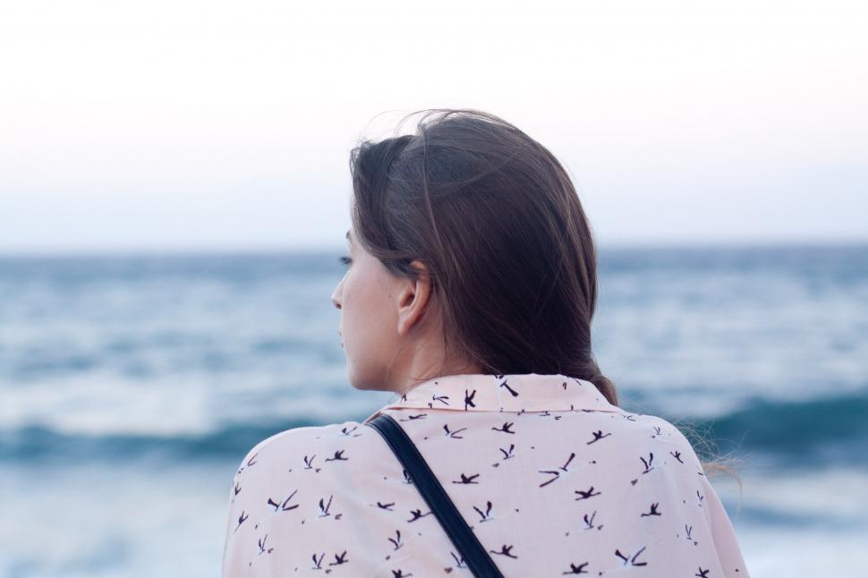 Free Image of Woman Standing on Beach Looking at Ocean 