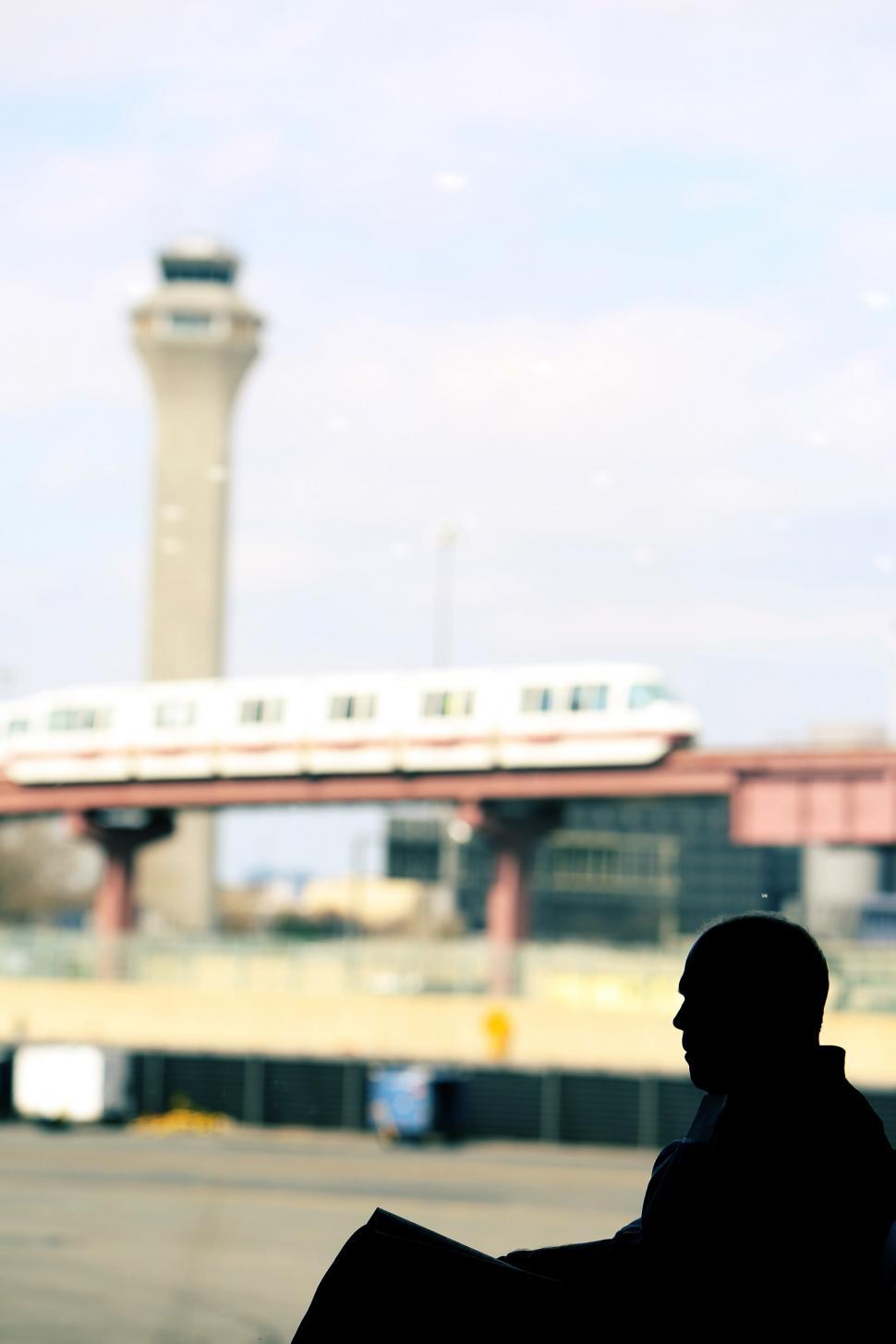 Free Image of Man Sitting on Bench in Front of Airport 