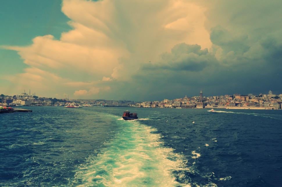 Free Image of Boat Traveling Down a Body of Water Under a Cloudy Sky 