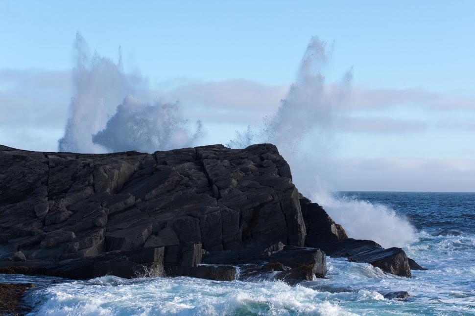 sea with big waves crashing to shore and rocks