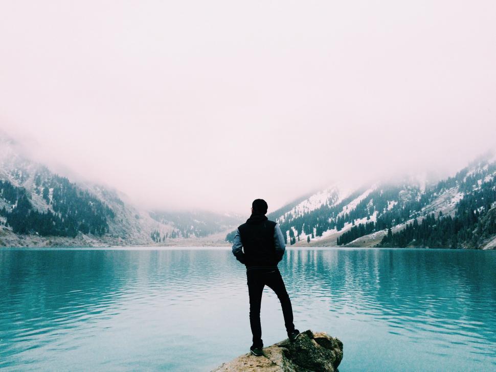 Free Image of Man Standing on Rock by Water 