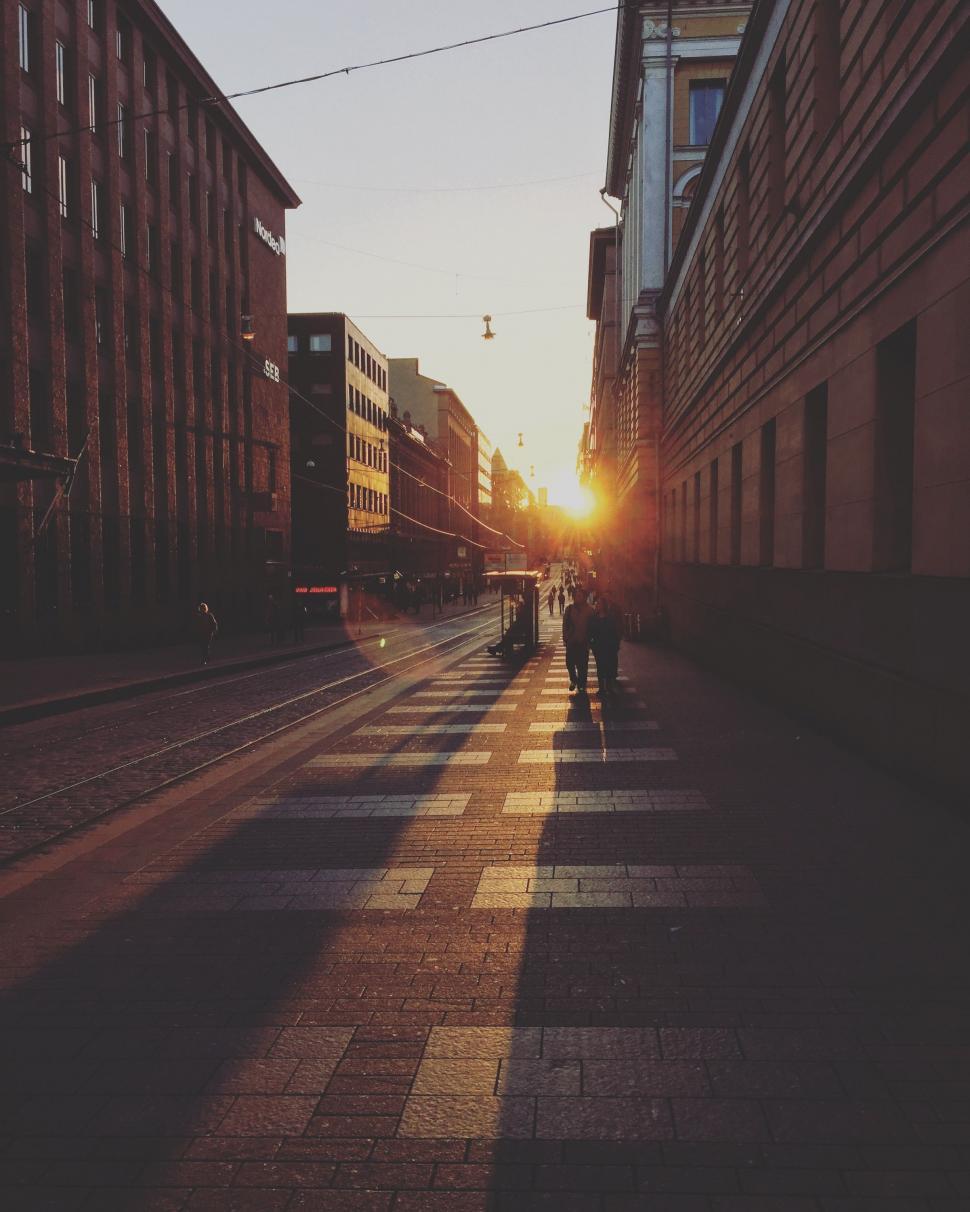 Free Image of Couple Walking Down City Street Among Tall Buildings 