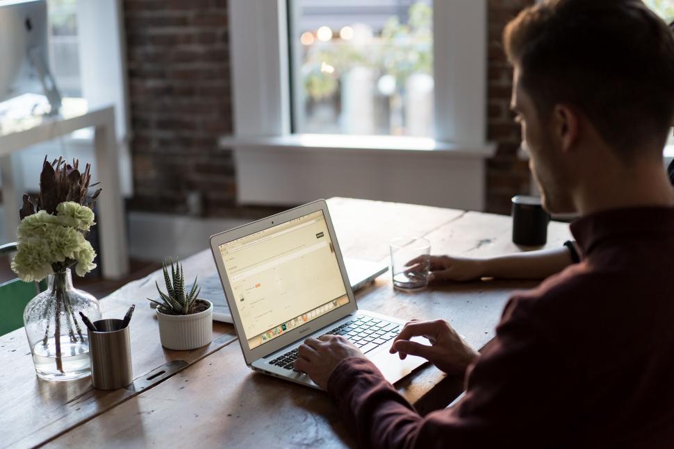 Free Image of Man Sitting at Table Using Laptop Computer 