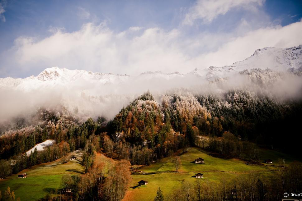 Free Image of Mountain Covered in Clouds and Trees Under Blue Sky 
