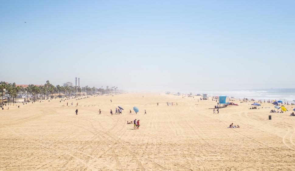 Free Image of Group of People Walking Along Sandy Beach 