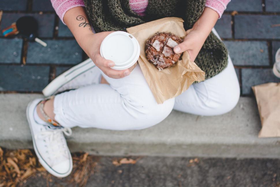 Free Image of Woman Sitting on Curb Holding Coffee Cup 