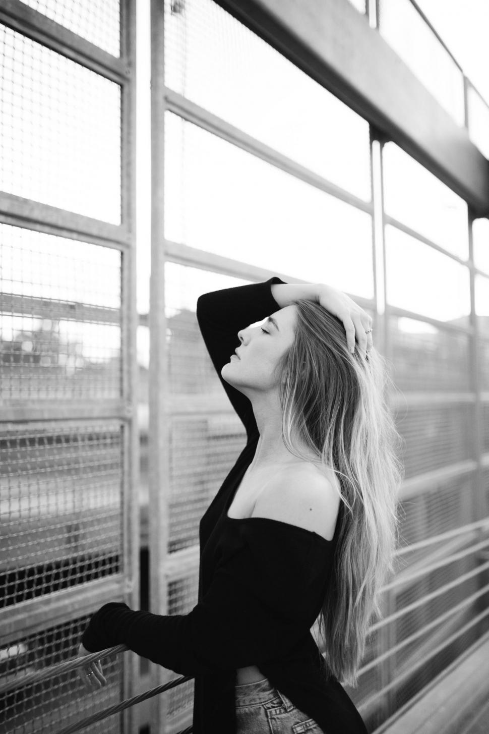 Free Image of Woman With Long Hair Leaning Against a Fence 