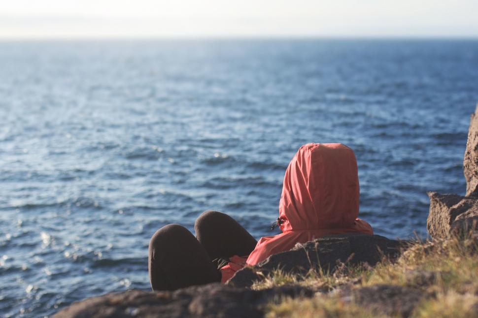Free Image of Person Sitting on Cliff Overlooking Ocean 