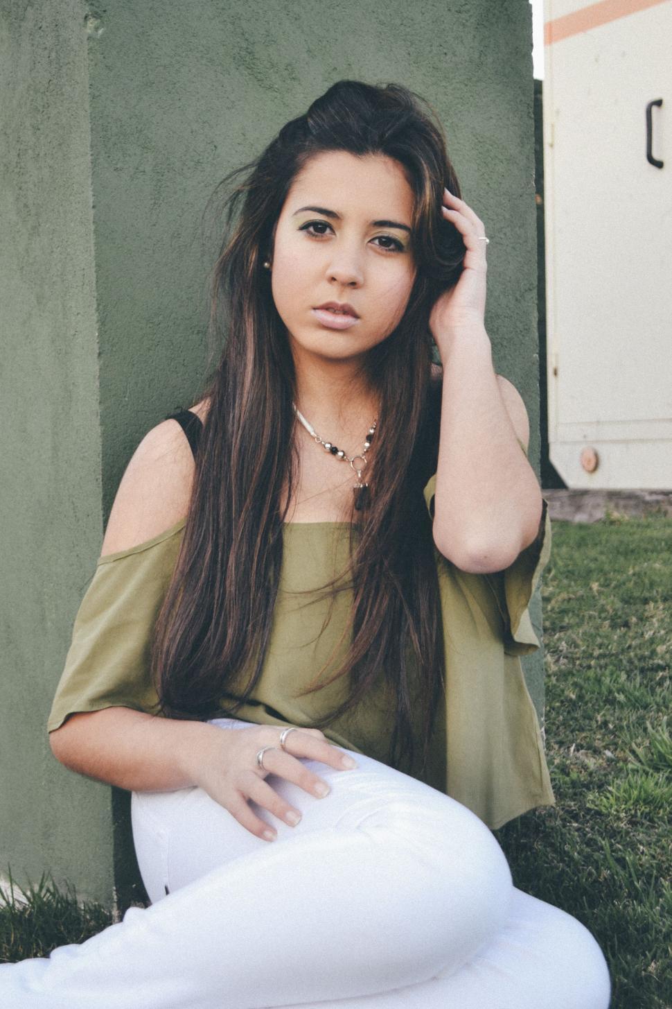 Free Image of Woman Sitting in Grass With Hand on Head 