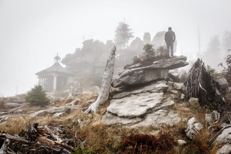 Free Image of Man Standing on Top of Rock Covered Hillside 