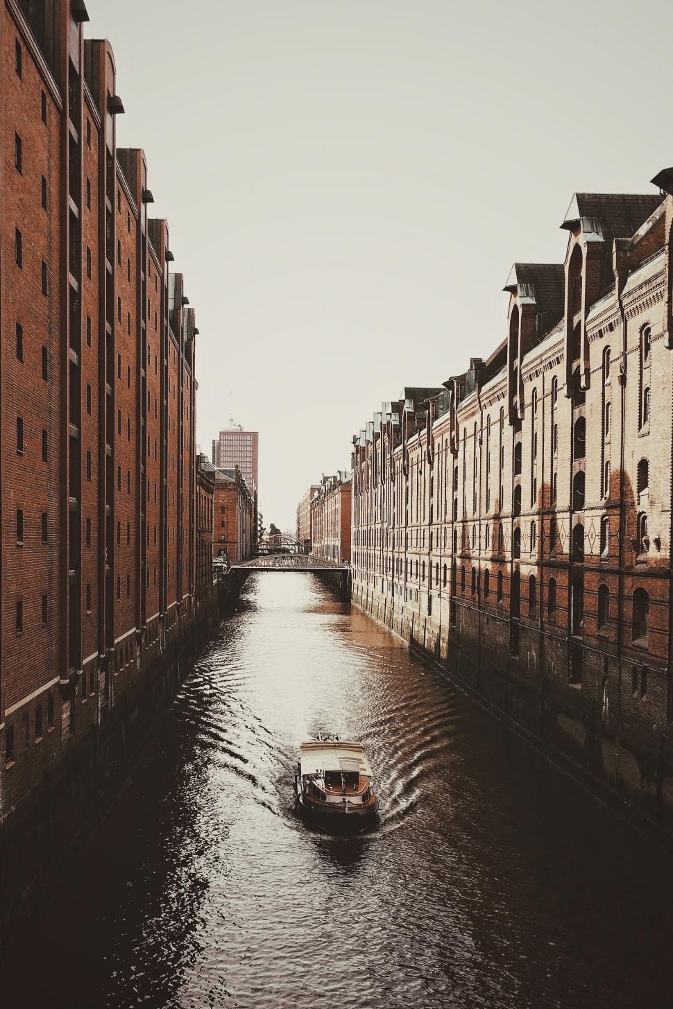 Free Image of Boat Traveling Down River Next to Tall Buildings 