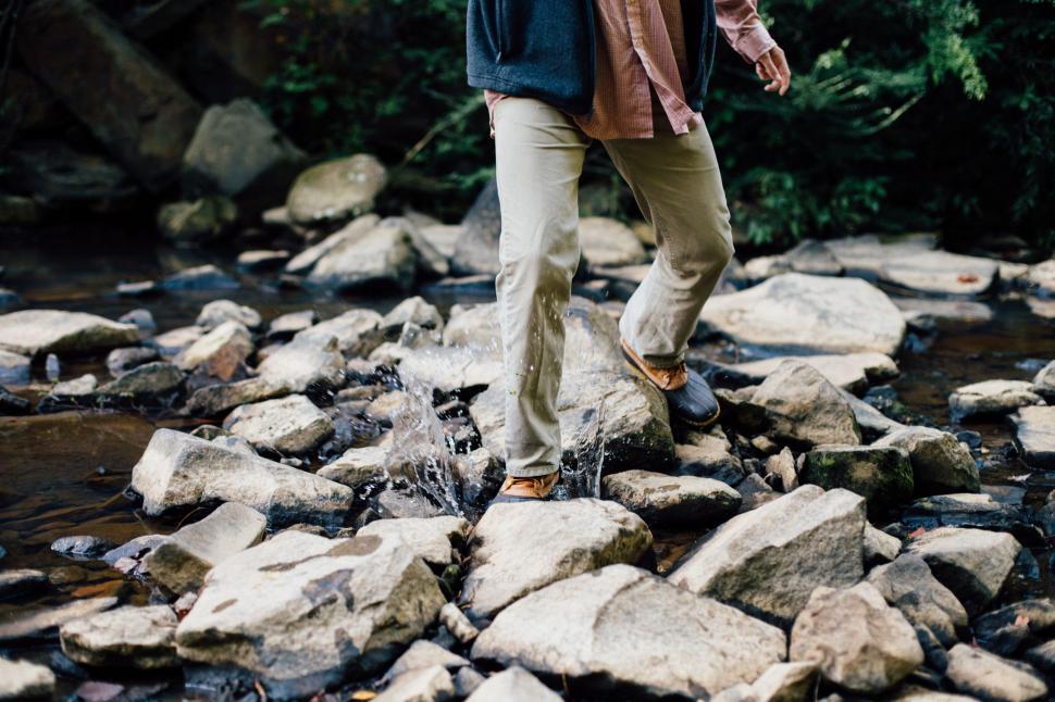 Free Image of Man Walking Across River Next to Forest 