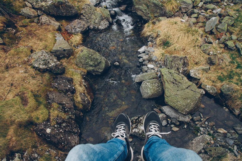Free Image of Person Standing on Rocky Hill by Stream 