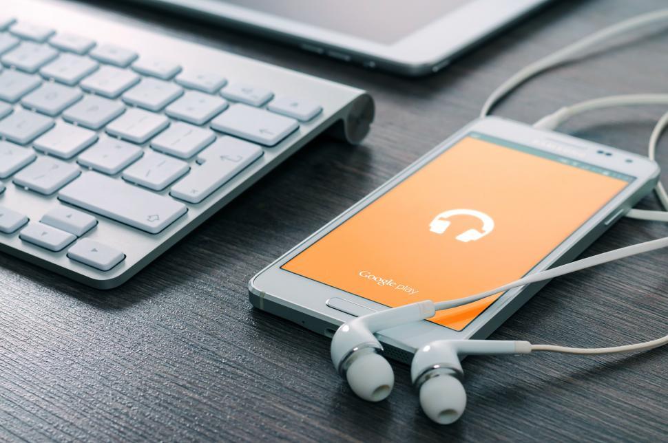 Free Image of Mobile device and earbuds on the desk 