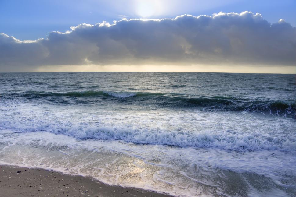 Free Image of Sun Shines Through Clouds Over Ocean 