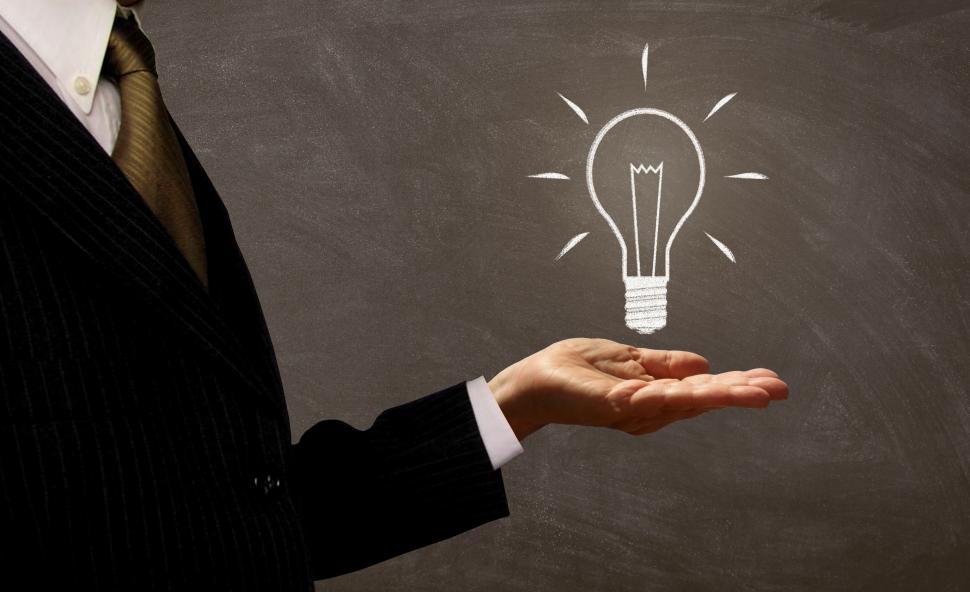Free Image of Businessman Holding Light Bulb on Chalkboard 