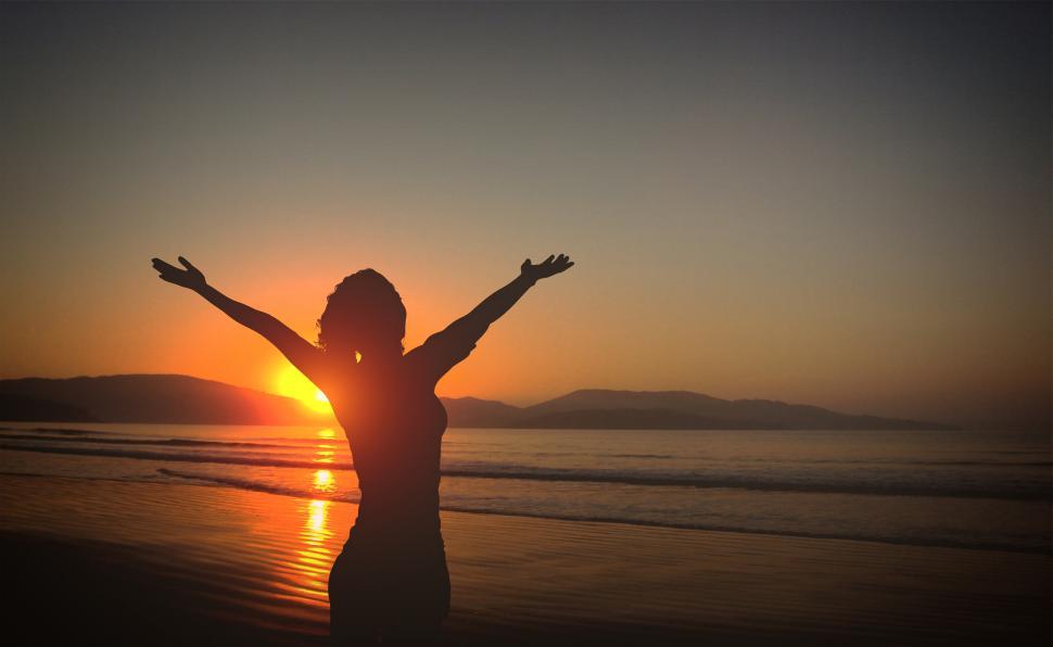Free Image of Young Woman on the Beach at Sunset with Raised Arms 