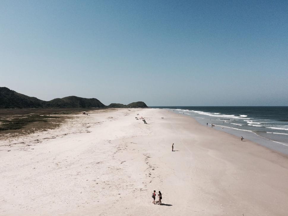 Free Image of People Walking on Sandy Beach 