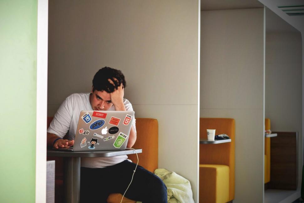 Free Image of Man Sitting at Table Using Laptop Computer 