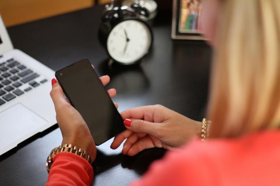 Free Image of Woman Sitting at Desk Using Cell Phone 