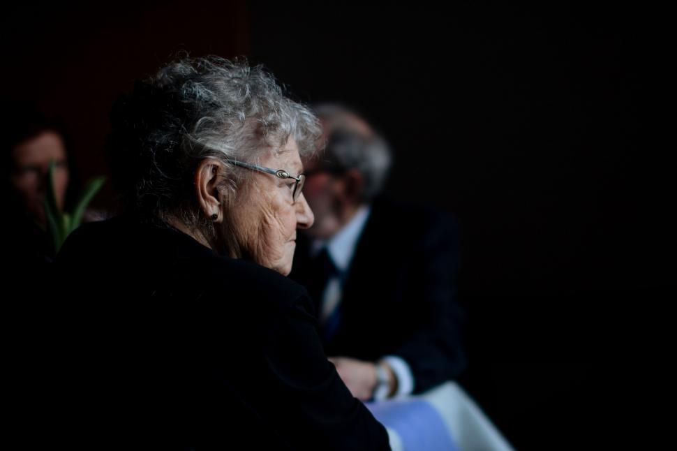Free Image of Old Man Sitting in Chair in Dark Room 