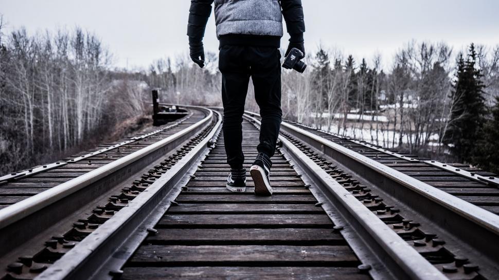 Free Image of Man Walking Down Train Track With Umbrella 