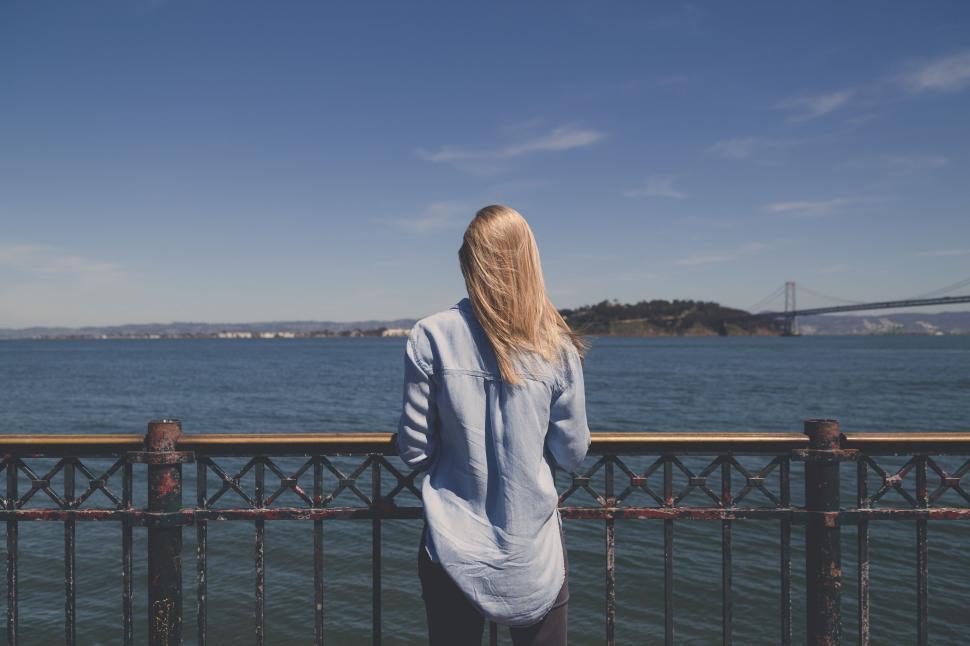 Free Image of Woman Standing on Bridge Looking at Water 