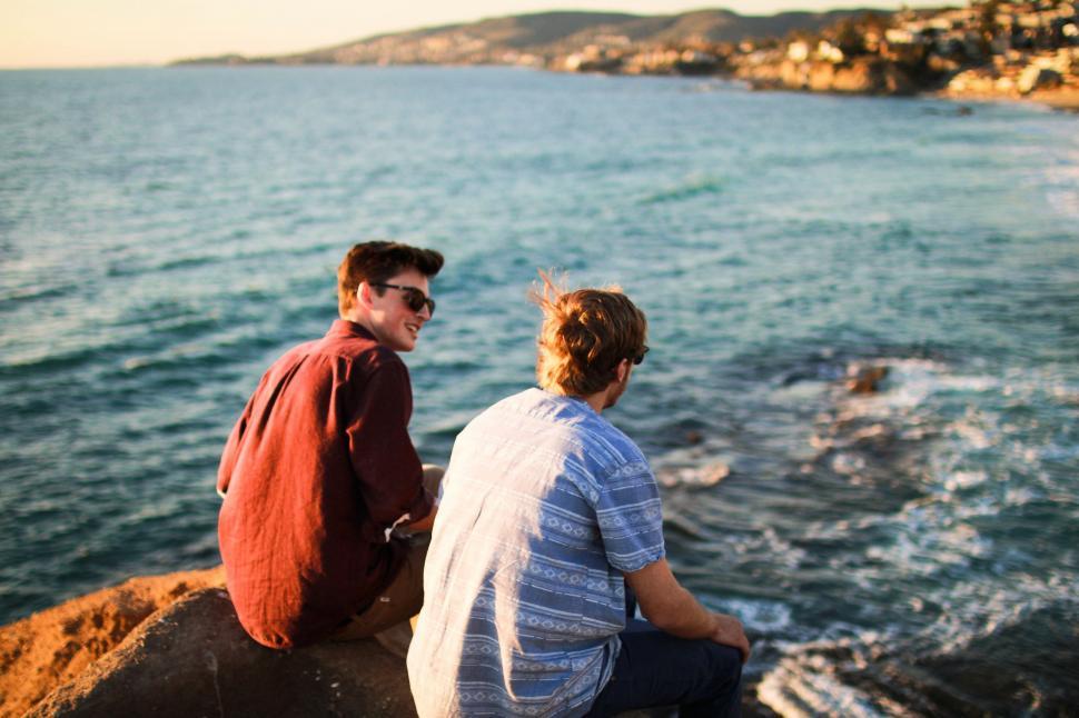 Free Image of Couple Sitting on Top of Rock by Ocean 