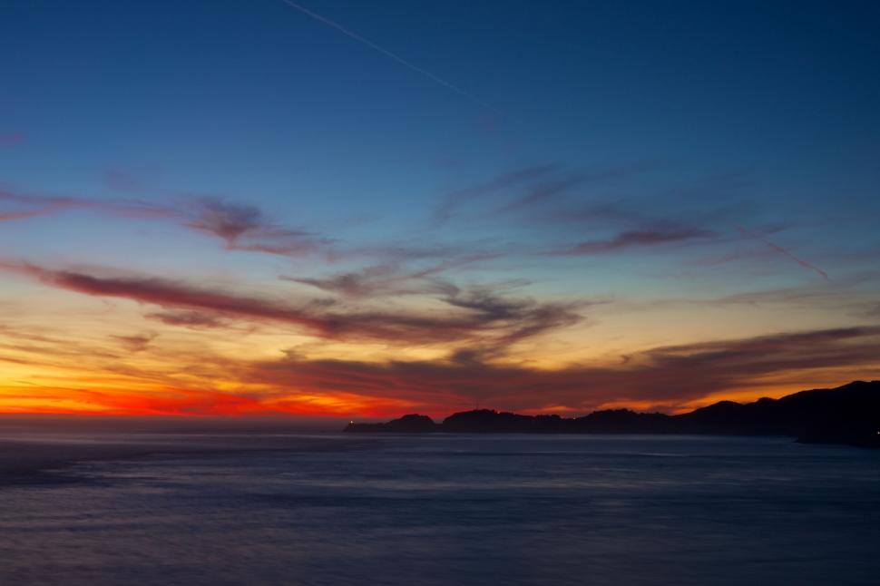 Free Image of Sun Setting Over Ocean With Clouds in Sky 