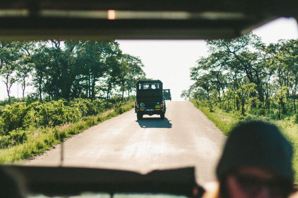 Free Image of Truck Driving Down Road Next to Lush Green Forest 