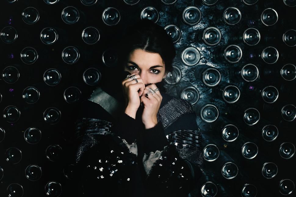 Free Image of Woman Standing in Front of Wall of Wine Glasses 