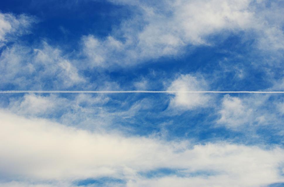 Free Image of A Plane Flying Through a Cloudy Blue Sky 