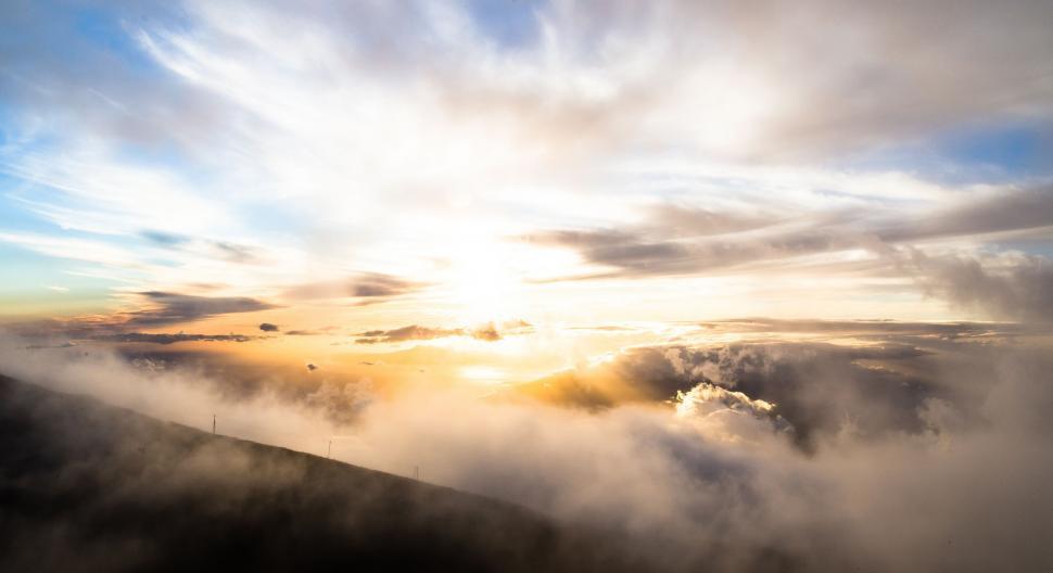 Free Image of Sun Shining Through Clouds Above Mountain 