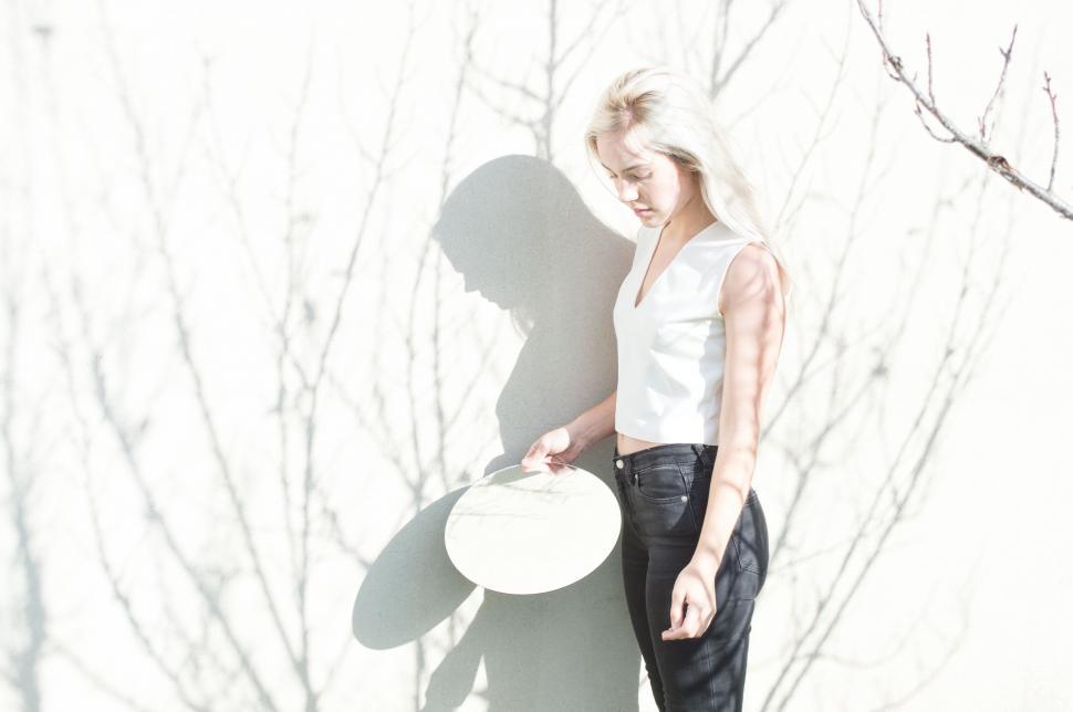 Free Image of Woman Holding White Frisbee Next to Tree 