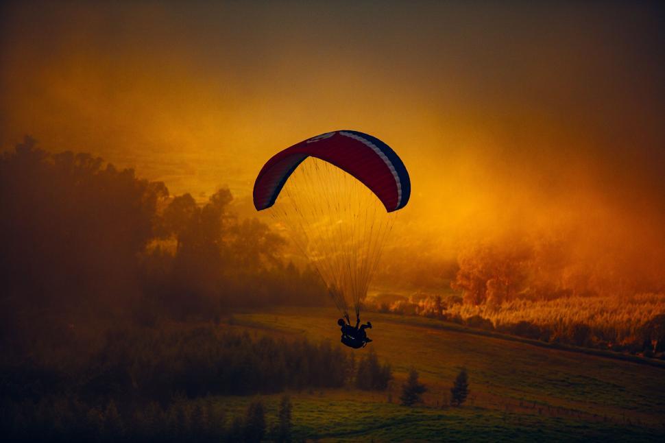 Free Image of Person Parasailing in Sky at Sunset 