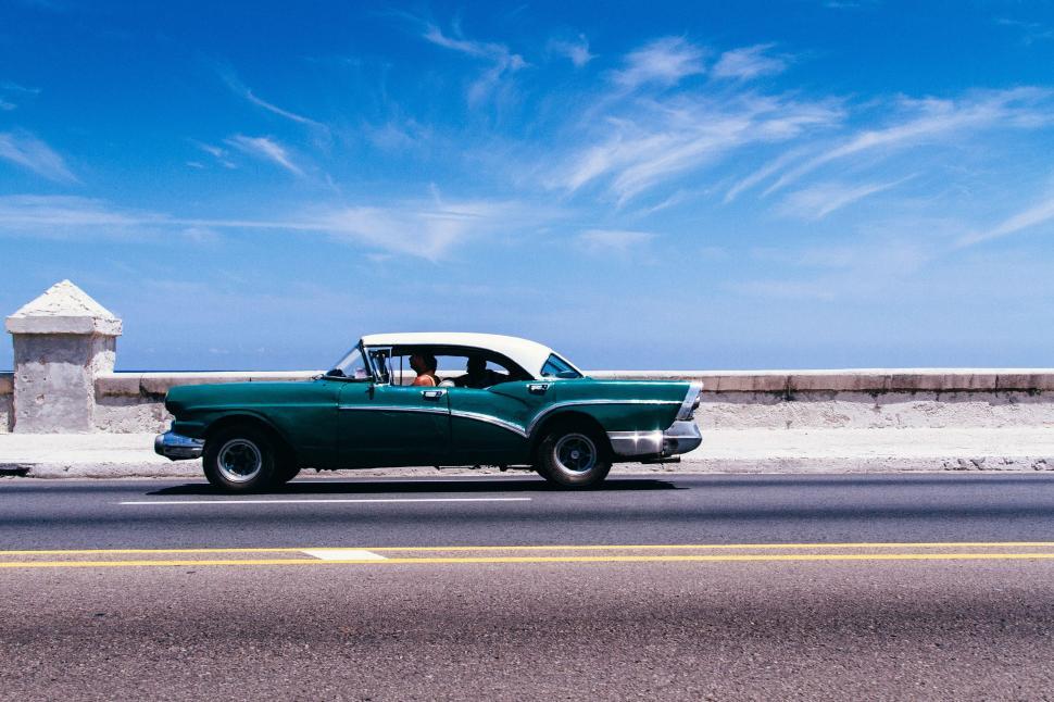 Free Image of Green Car Driving Down Coastal Road 