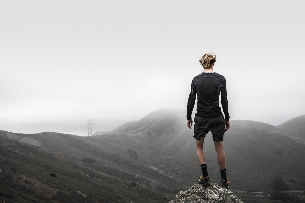 Free Image of Man Standing on Top of Rock in the Mountains 