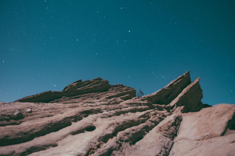 Free Image of Person Standing on Top of Mountain Under Blue Sky 