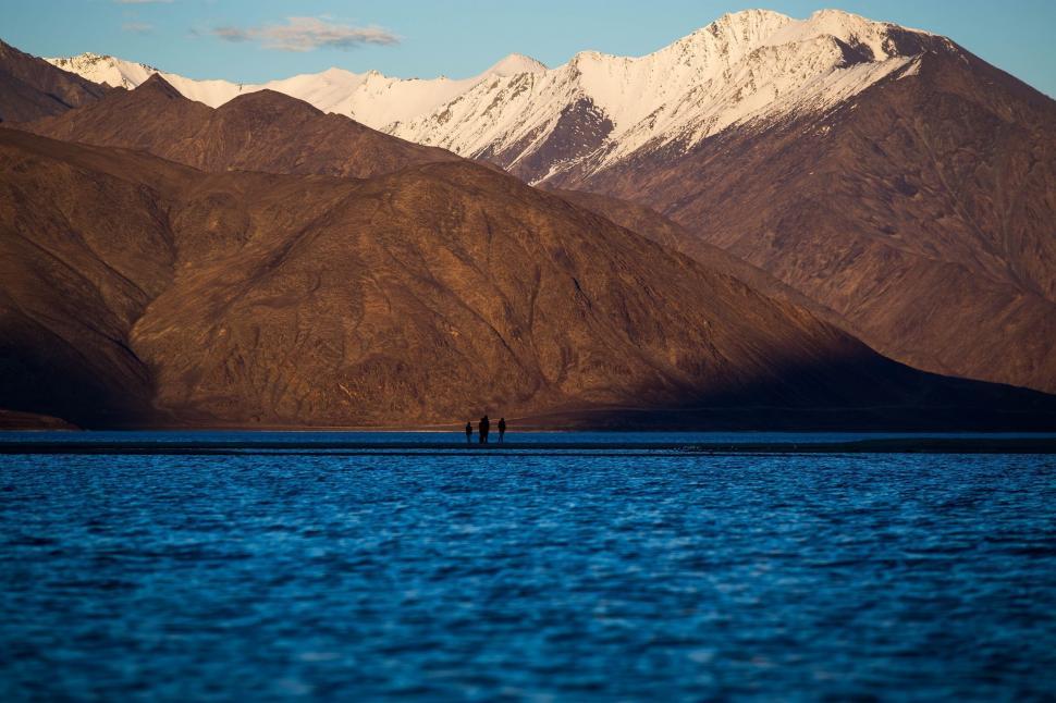 Free Image of Couple Standing on Top of Large Body of Water 