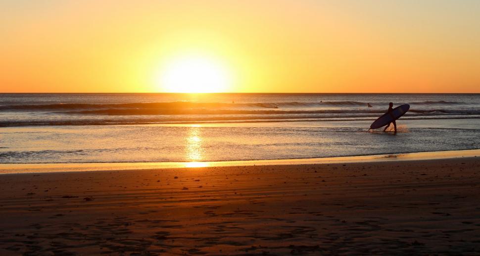 Free Image of Person Carrying Surfboard Into Ocean at Sunset 